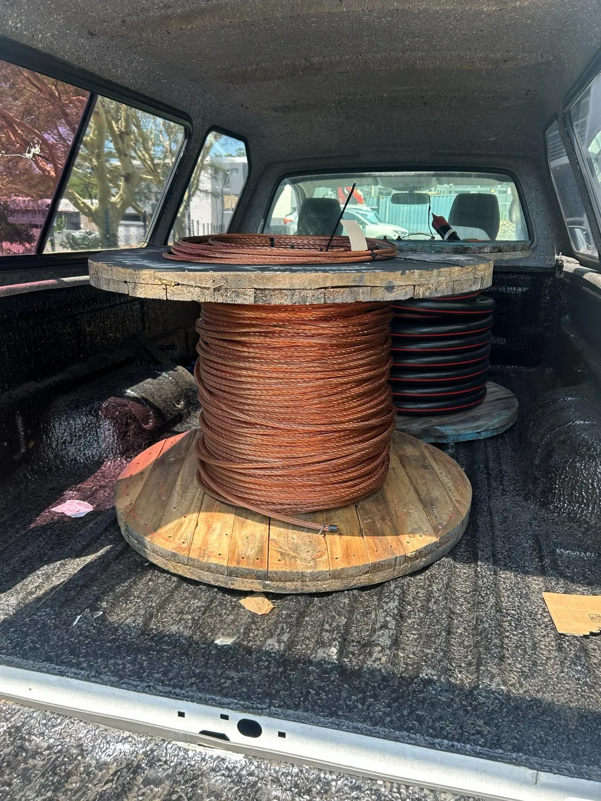A drum of bare stranded copper conductor loaded in a vehicle load bed.