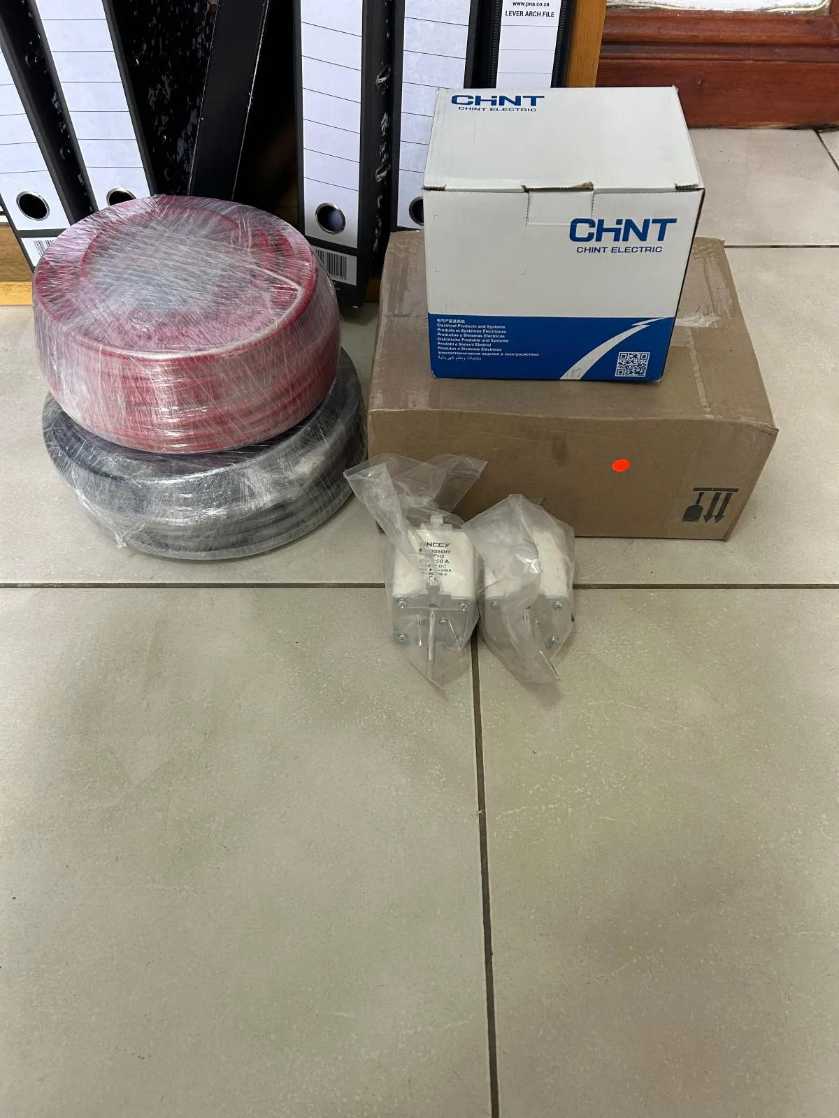 Wrapped coils of red and black cable alongside boxed electrical components and bagged fuse links