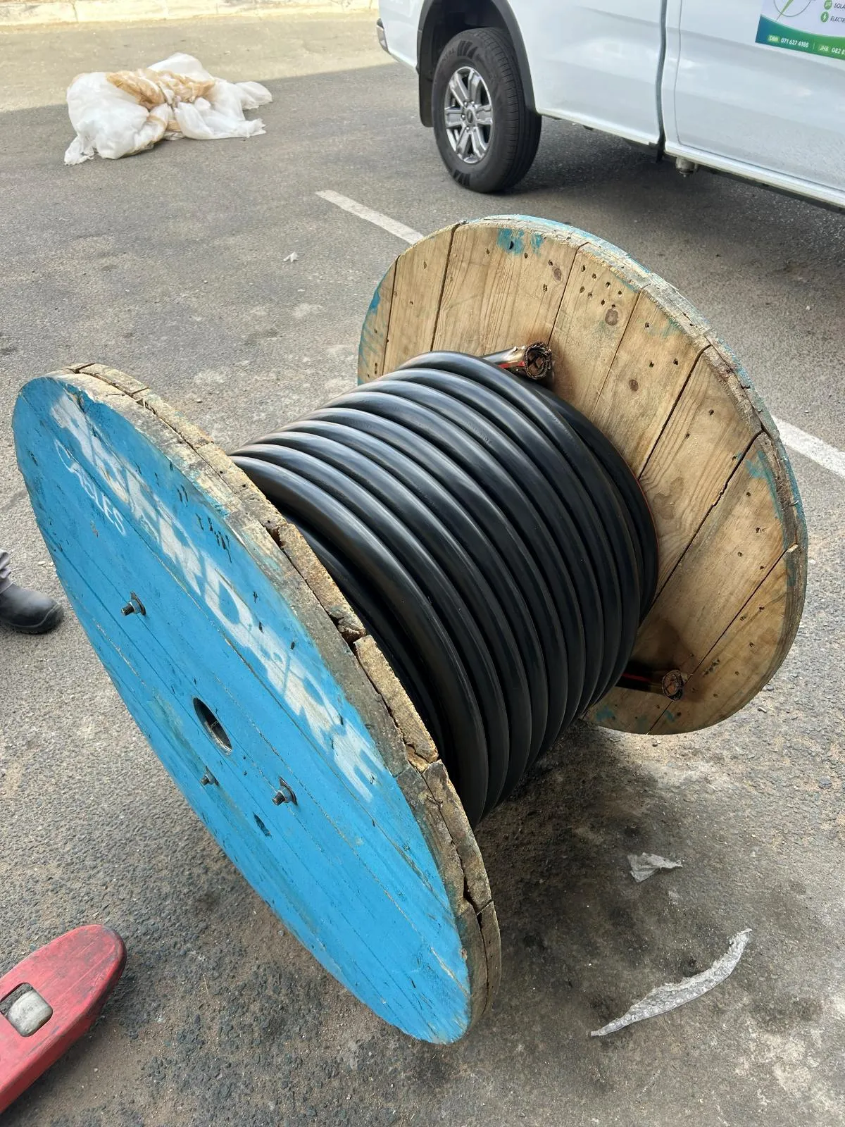 A blue-ended drum of black cable standing beside an Era-Sure branded vehicle.