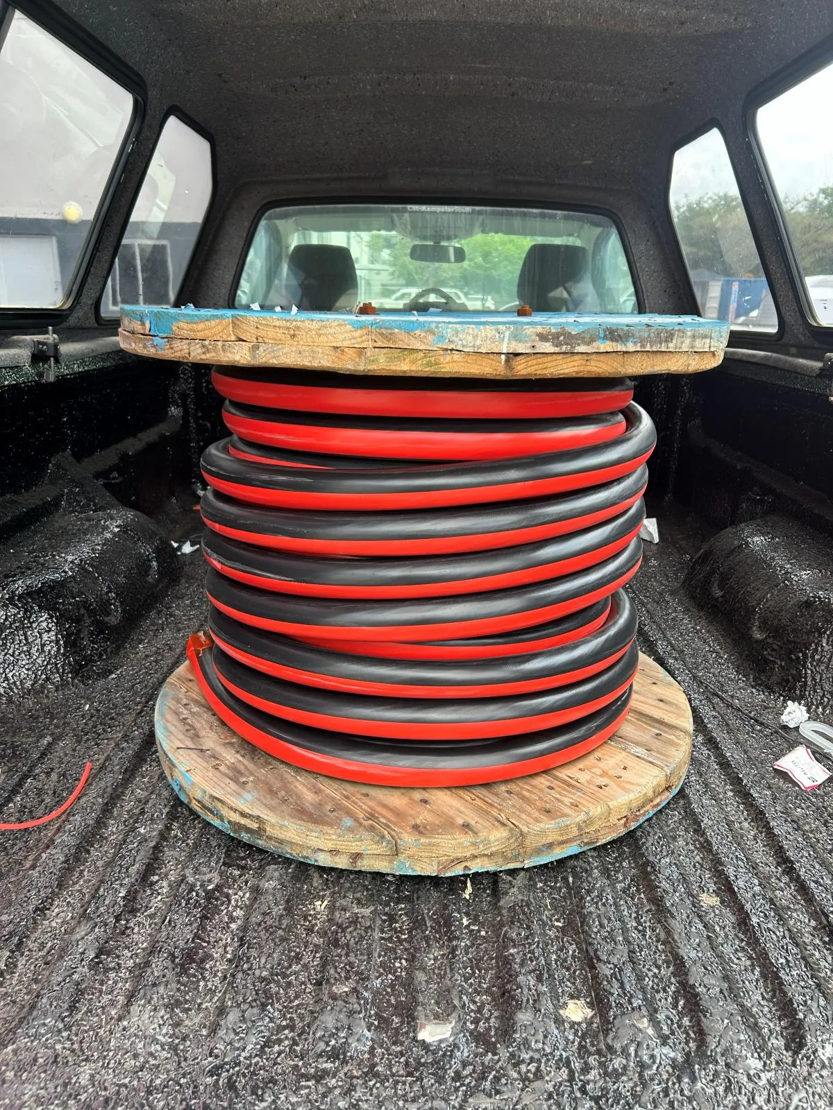 A coil of alternating red and black cable on a drum in a vehicle load bed.