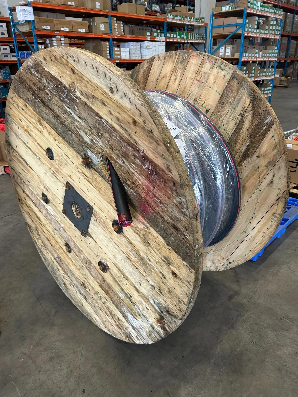 Two large cable drums resting in a warehouse aisle beside stocked racking.