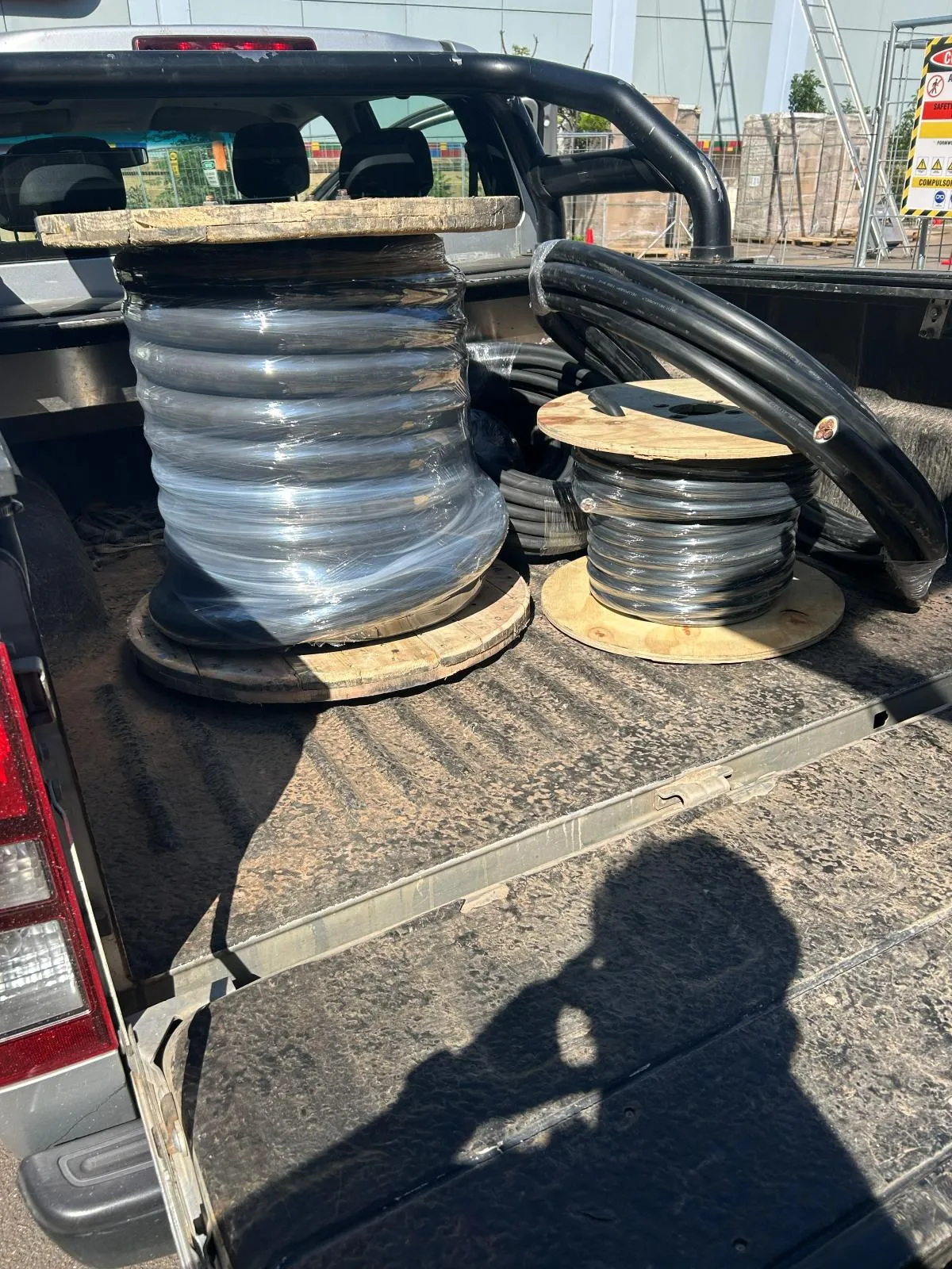 Reels of clear-sheathed and black cable loaded in a vehicle load bed.