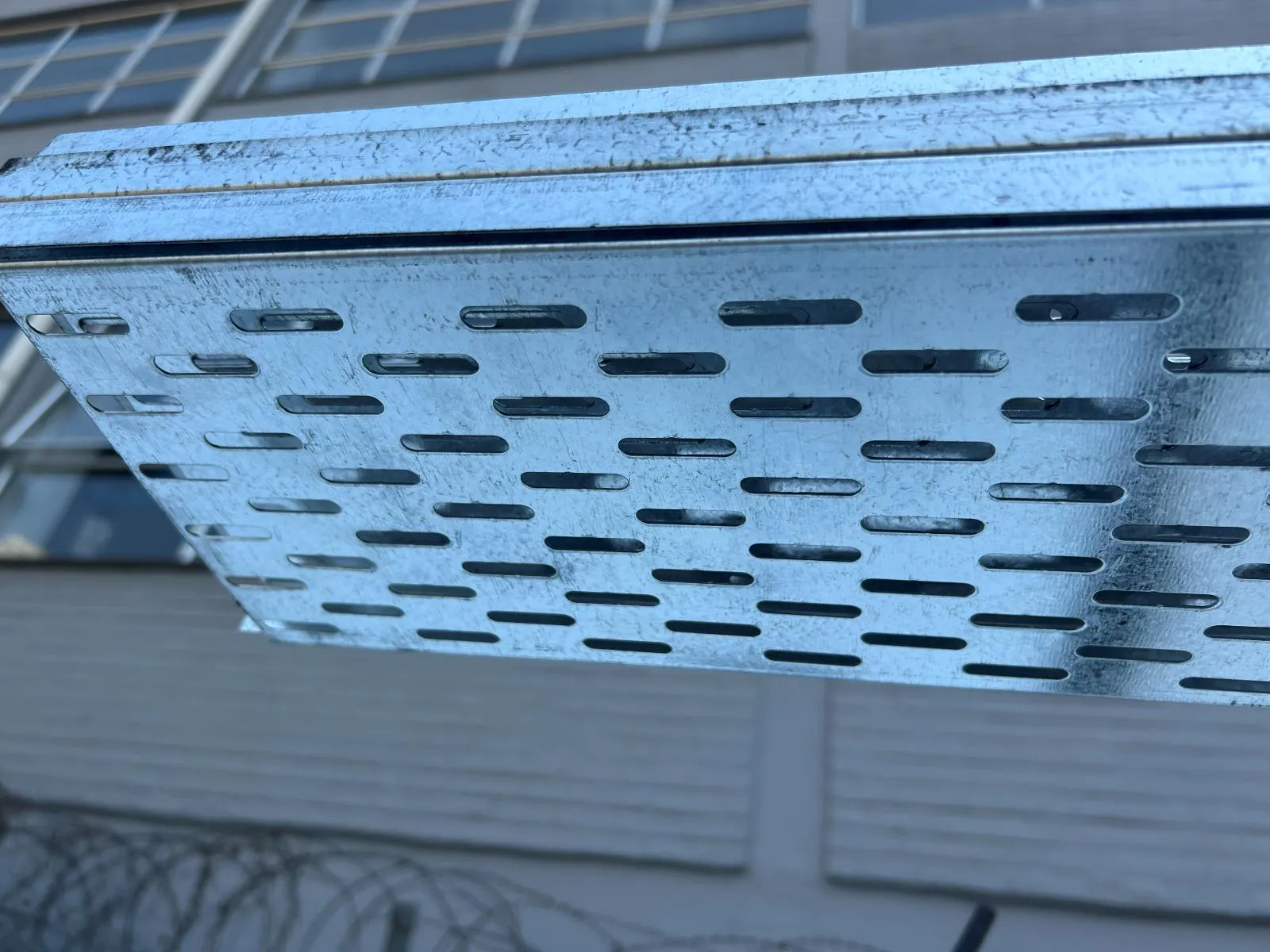Close view of the slotted perforations and returned edge of a galvanised cable tray.