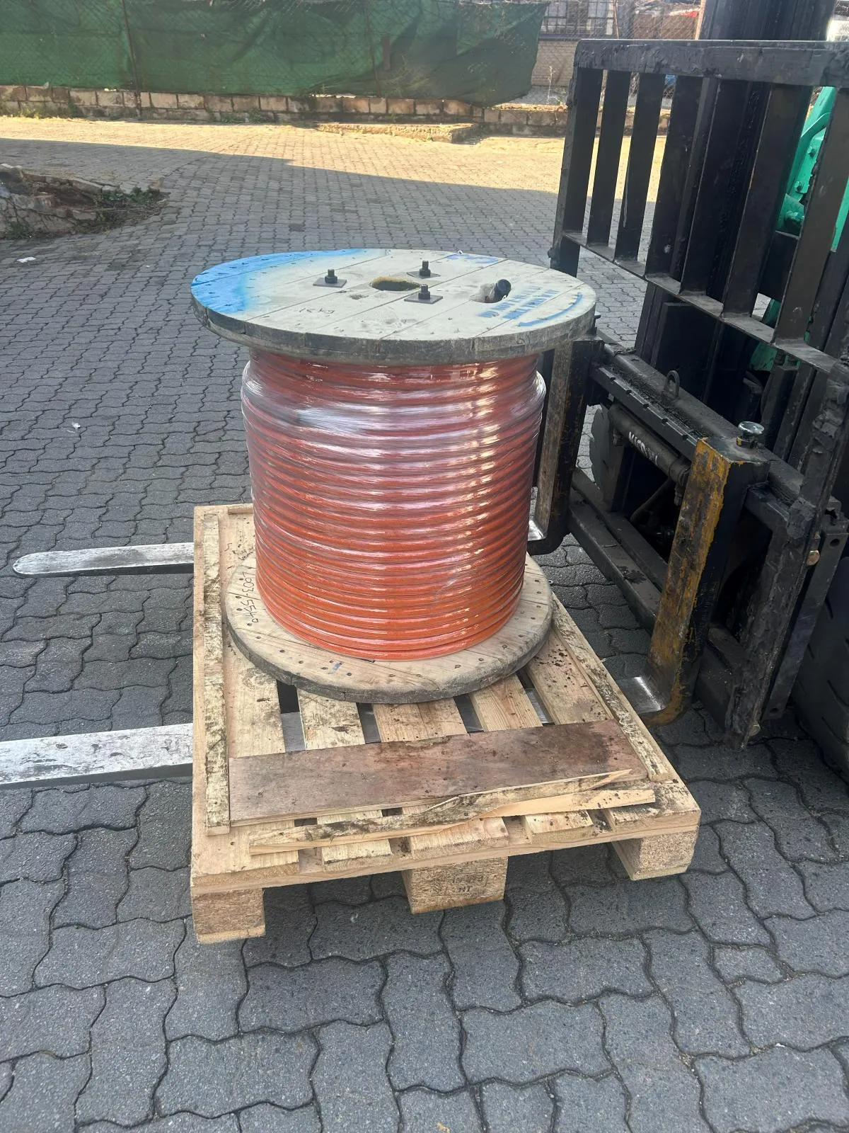 A reel of copper-coloured cable on a pallet raised on forklift tines.