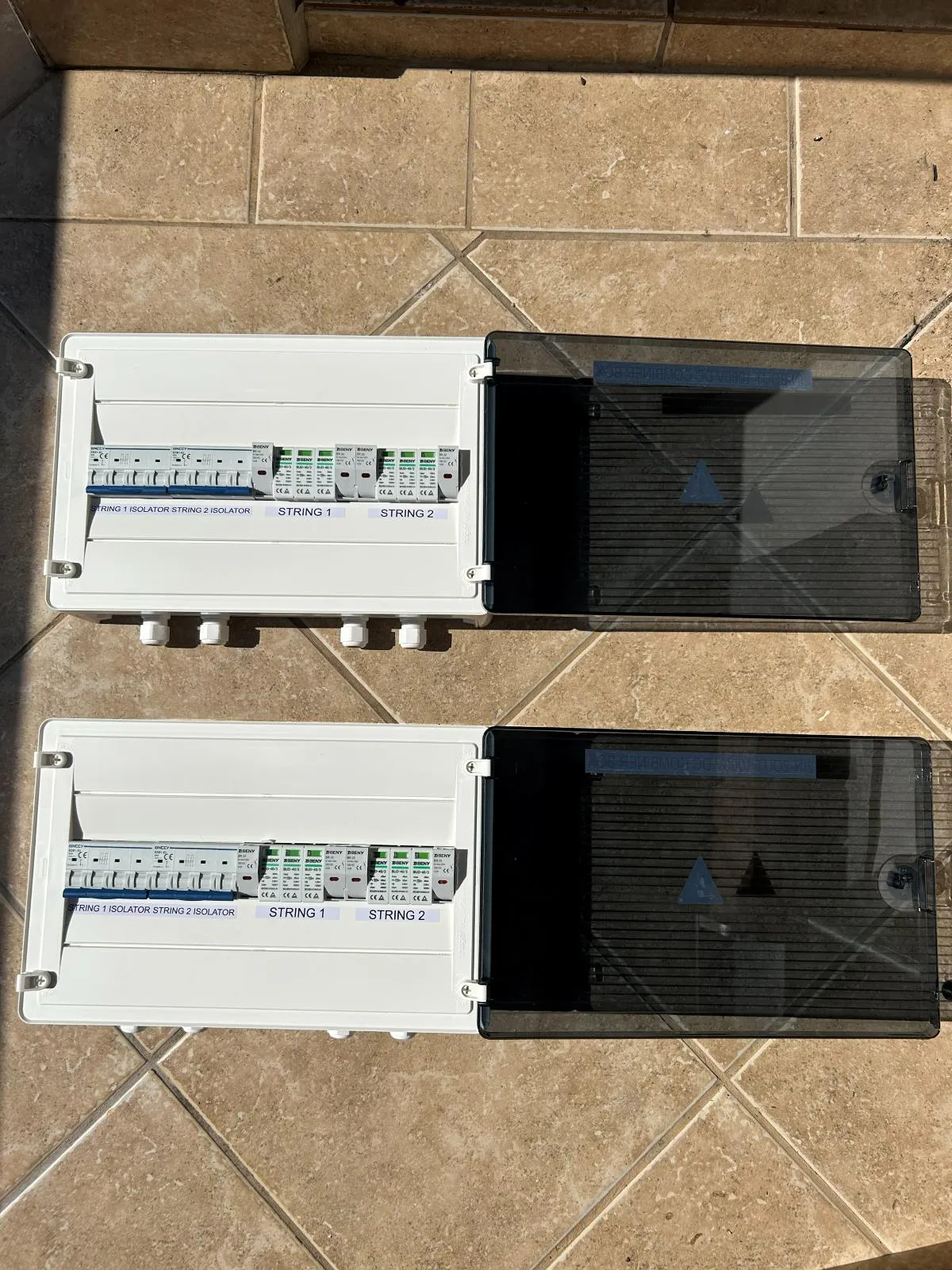 String isolators and protection devices on the DIN rail inside two open DC combiner boxes.