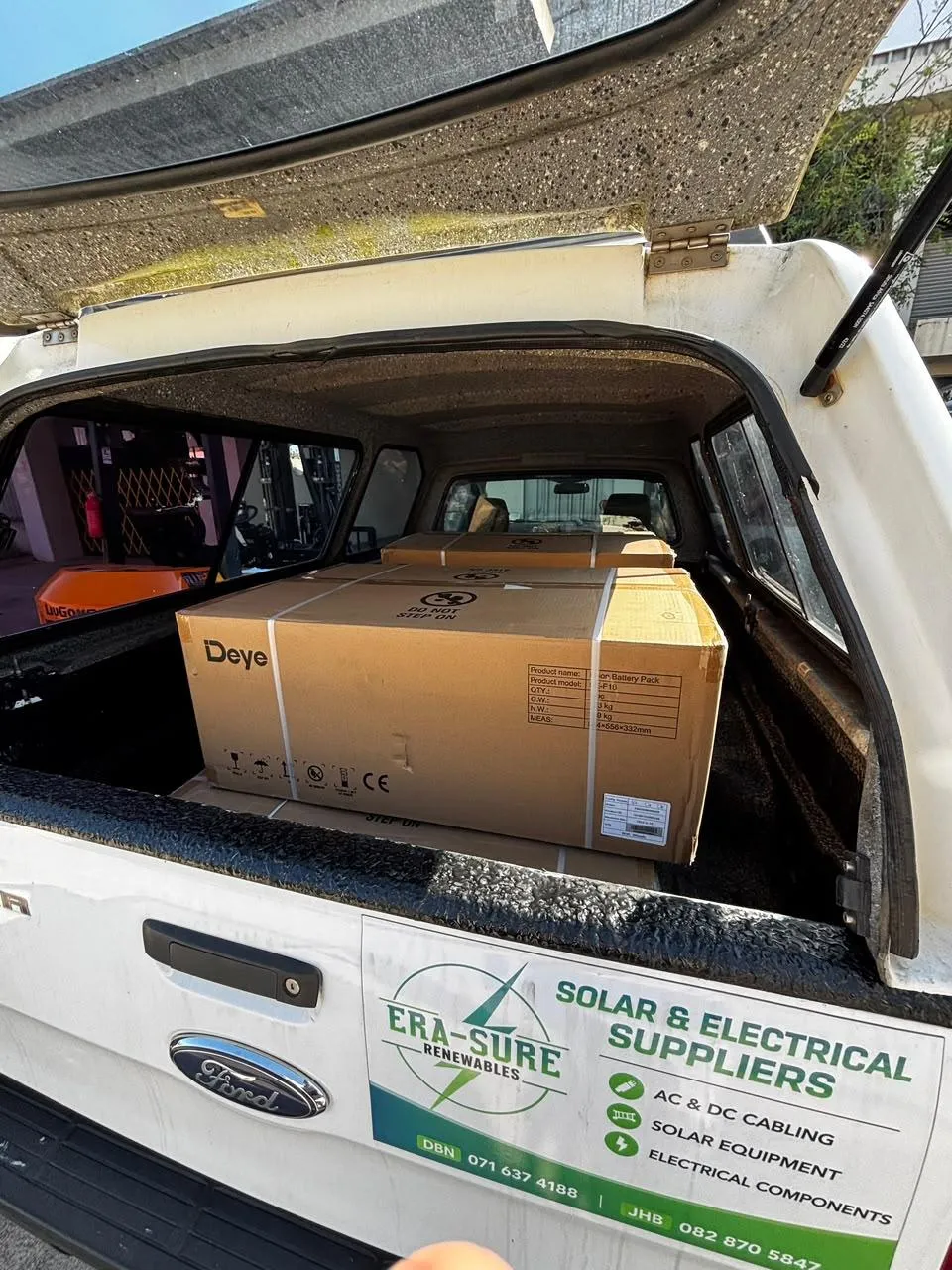 Boxed Deye battery packs loaded beneath the canopy of an Era-Sure delivery vehicle