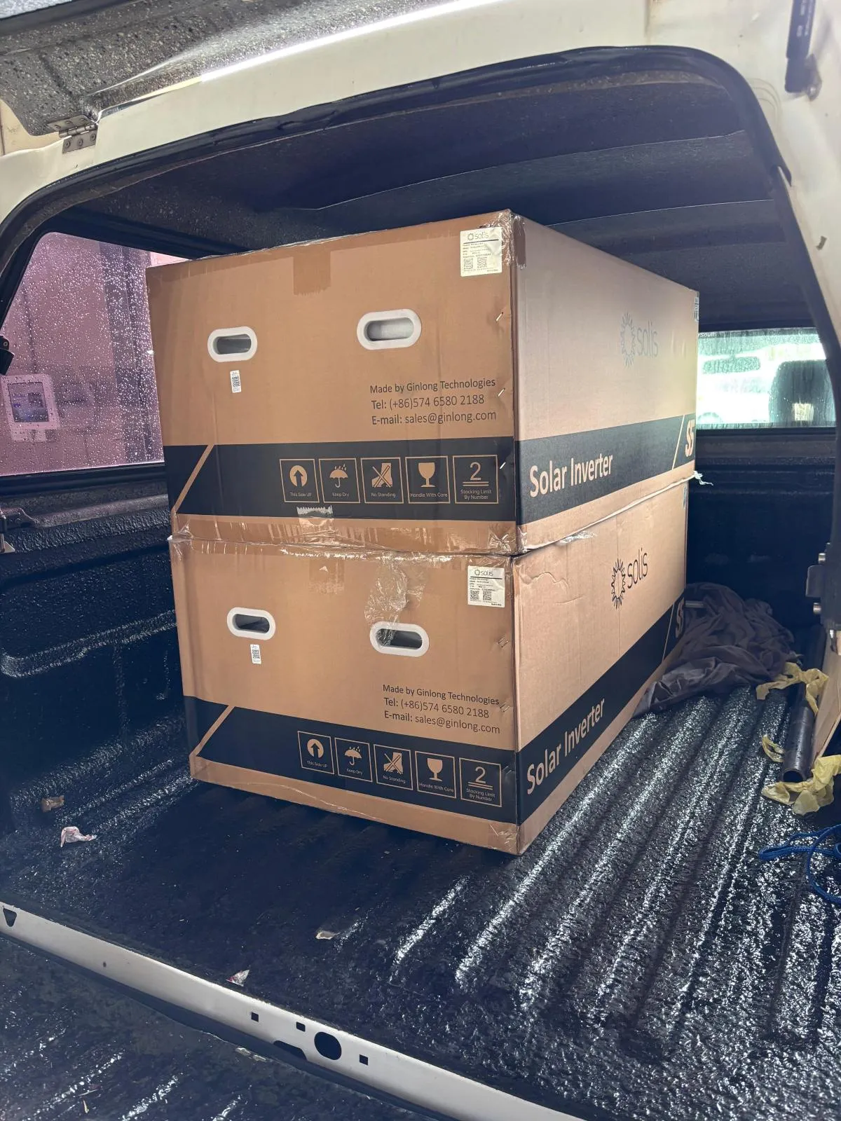 Two boxed Solis solar inverters strapped upright in a vehicle load bed